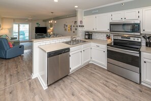 A modern kitchen with white cabinetry, stainless steel appliances, and a built-in dishwasher.