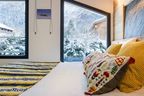 Ein Schlafzimmer mit einem Bett, einem Fenster mit Blick auf Schnee und einem Bild an der Wand.