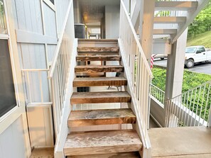 Eine Holztreppe mit weißen Geländern führt zu einem Balkon.