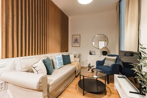 Ein modernes Wohnzimmer mit einer Couch, Sesseln, einem Couchtisch, einem Spiegel und einer Pflanze.