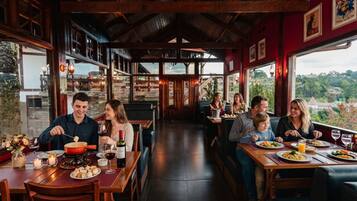 A restaurant with wooden interiors, large windows, and a view of the countryside.