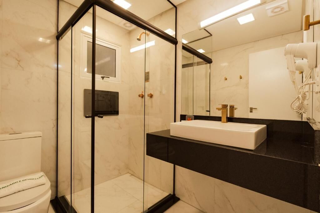 A modern bathroom with a glass-enclosed shower, a white sink, and a mirror.