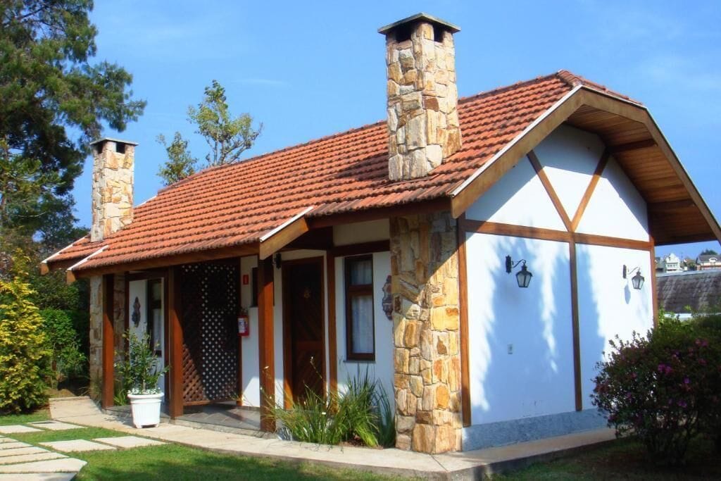 A stone building with a red-tiled roof, a wooden porch, and a white exterior.