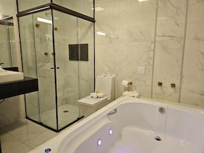 Ein Badezimmer mit einer Glaskabinentasse, einer weißen Badewanne und Marmorwänden.