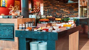 A buffet counter with various food items, a clock, and a sign indicating the room number. - Pousada Recanto dos Sonhos (Campos do Jordão)