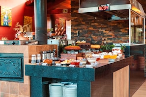 A buffet counter with various food items, a clock, and a sign indicating the room number. - Pousada Recanto dos Sonhos (Campos do Jordão)