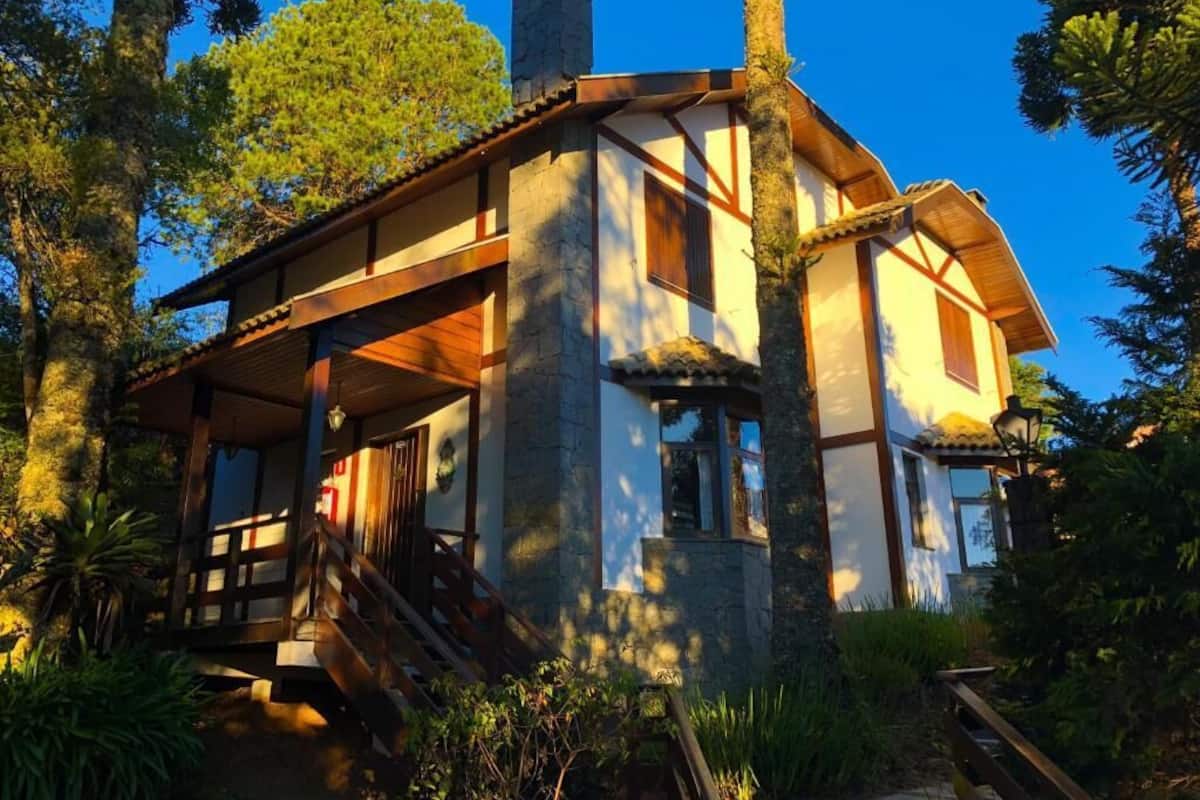 A rustic cabin with a stone exterior, wooden beams, and a staircase leading to the entrance.