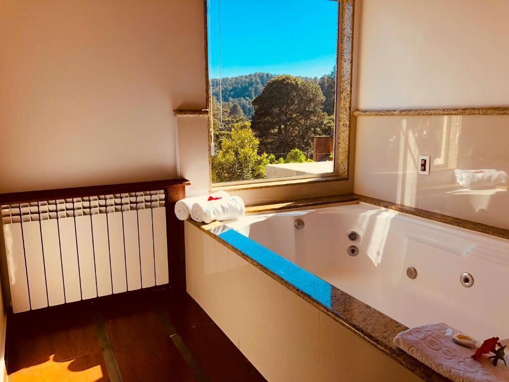 Une salle de bain avec une baignoire, une fenêtre donnant sur les arbres et une serviette posée sur le bord.