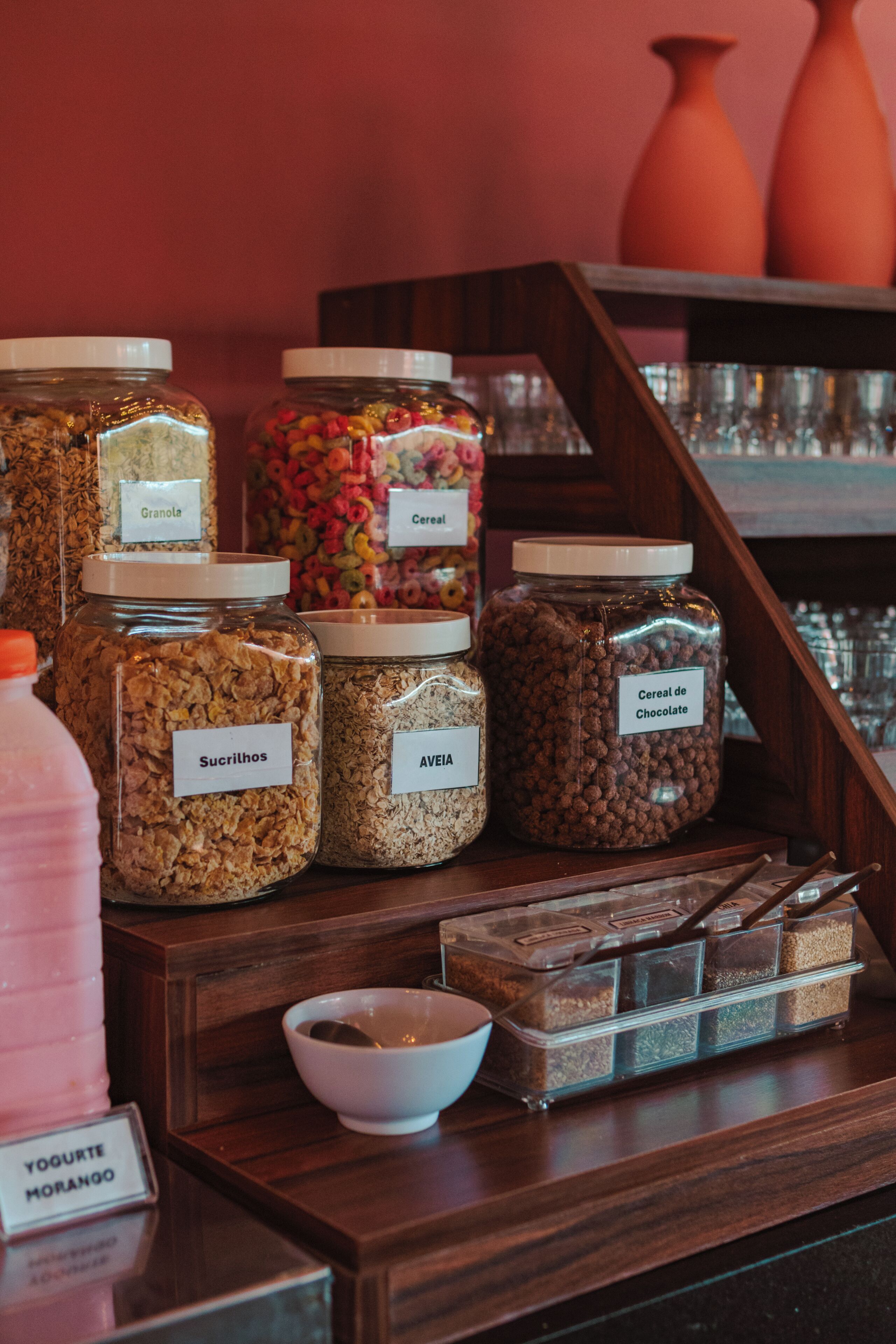 Une présentation de divers aliments présentés dans des bocaux étiquetés, un saladier et une boîte de barres chocolatées.