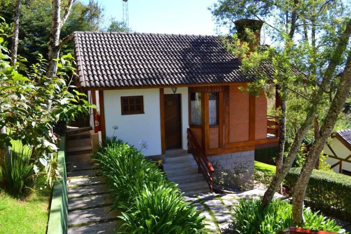 A small, single-story house with a tiled roof, a wooden front porch, and a stone foundation.
