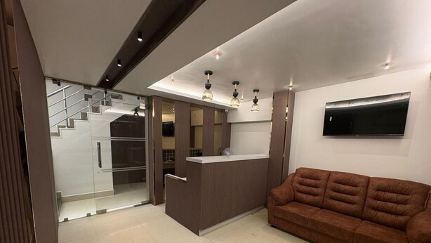 A modern interior with a sofa, a counter, and a staircase. - Hotel Royal King (Chennai)