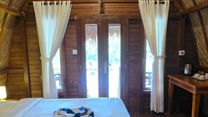 Una habitación acogedora y rústica con techo de madera, una cama grande con manta a rayas y una mesita con lámpara.
