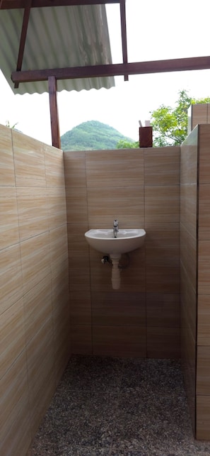 Un baño con lavamanos, paredes de azulejos y vistas a la montaña.