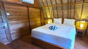Habitación con estructura de madera, una cama, mesitas de noche y aire acondicionado instalado en la pared.