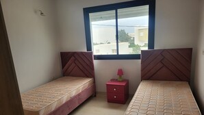 Una camera da letto con due letti, un comodino e una finestra.