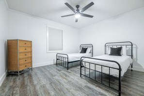 A bedroom with two metal beds, a wooden dresser, a ceiling fan, and a window with blinds. - Smoky Pines Retreat, Sleeps 10, Hot Tub, Balcony (Sevierville)
