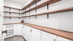Una cocina con armarios blancos, encimeras de madera y vigas a la vista.