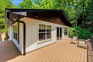 Eine Hütte mit einer Veranda, großen Fenstern und einem überdachten Bereich.