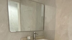 A bathroom with a large mirror, a sink, and a faucet. - Alsumo Suites (Ha'il)