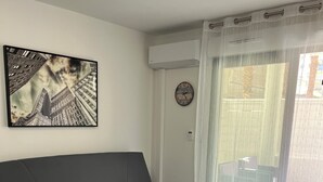 A modern living room with a grey sofa, a wooden coffee table, and a cityscape painting on the wall. - Studio parking clim wifi parking downtown (Béziers)