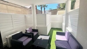 A small, enclosed patio area with wicker furniture and a green artificial turf floor. - Studio parking clim wifi parking downtown (Béziers)
