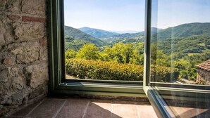 Ein Zimmer mit großem Fenster und Blick auf eine gebirgige Landschaft.
