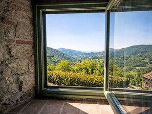 Ein Zimmer mit großem Fenster und Blick auf eine gebirgige Landschaft.