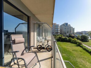 Ein Balkon mit einem Stuhl, einem Fahrrad und Blick auf ein Wohngebiet.