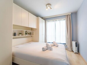 Ein Schlafzimmer mit Bett, Einbauschränken, Heizkörper und einem Fenster mit Vorhängen.