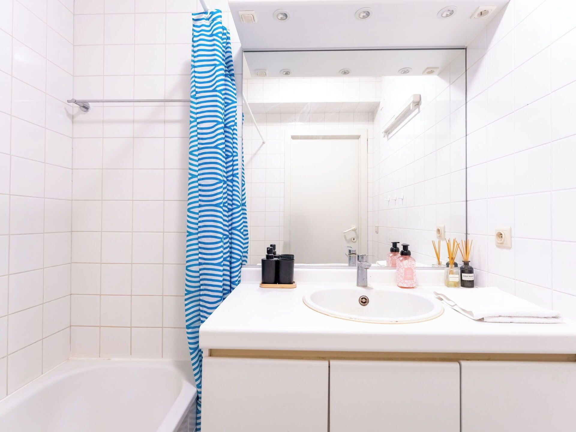 Ein Badezimmer mit einer Badewanne, einem Waschbecken mit Spiegel und Toilettenartikeln auf der Ablagefläche.