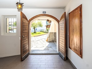 Un portail en arc surmonté d’un panneau indiquant un numéro, un cadre de porte en bois et un sol carrelé.