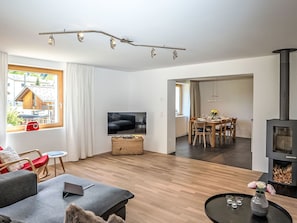 Un salon moderne comprenant un canapé, un coin repas avec une table et des chaises, un téléviseur et une cheminée.