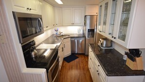 A kitchen with white cabinets, stainless steel appliances, and a granite countertop. - Edgewater House - Ocean Front Units With Spectacular Views! (Rehoboth Beach)