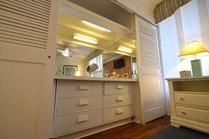 Ein Zimmer mit weißem Schminktisch, einem Spiegel, einer Lampe und einem Deckenventilator.