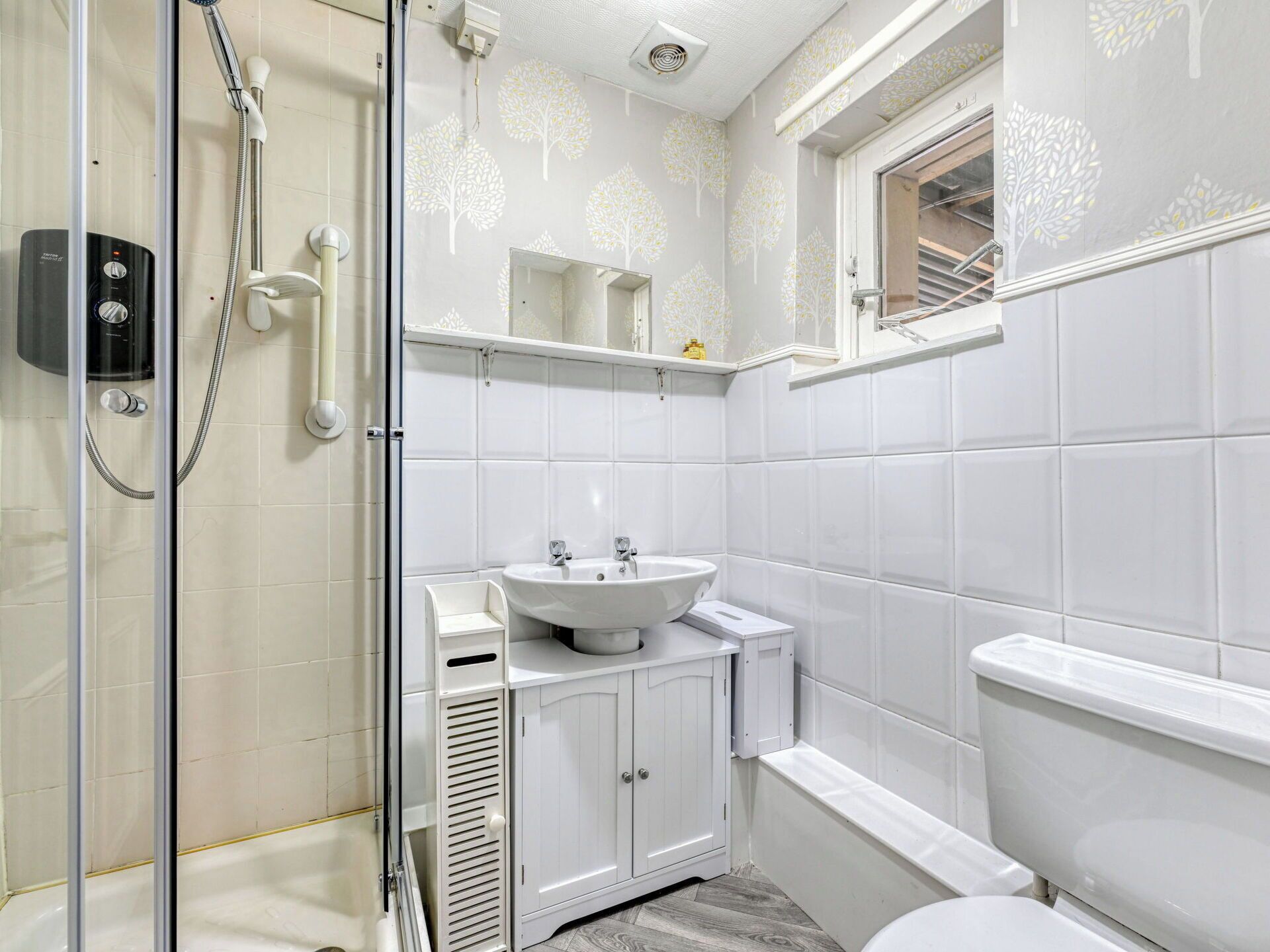 A bathroom with a glass shower enclosure, a white sink, a cabinet, and a toilet.