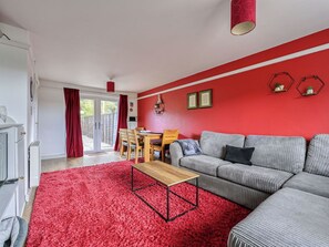Ein Wohnzimmer mit rotem Teppich, einer Couch, einem Holztisch und einem Essbereich mit Tisch und Stühlen.