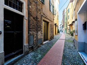 Eine enge Kopfsteinpflasterstraße, gesäumt von historischen Gebäuden mit steinernen Fassaden und traditionellen Fensterläden.