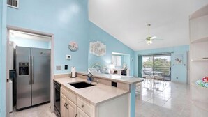 A modern kitchen with a stainless steel refrigerator, a sink, and a dining area with a table and chairs. - The Flip Flop - 1BR w/ beach & lake access (Ponte Vedra Beach)