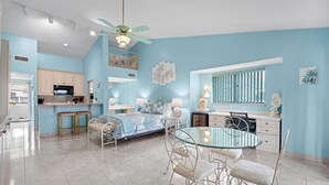 A modern bedroom with a bed, bedside tables, a glass dining table, and a ceiling fan. - The Flip Flop - 1BR w/ beach & lake access (Ponte Vedra Beach)
