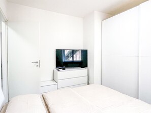 Ein Schlafzimmer mit einem Bett, einer Kommode und einem an der Wand befestigten Fernseher.