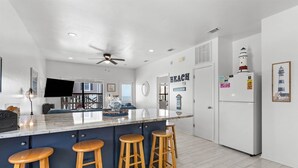 Una cocina moderna con una isla grande, taburetes de bar y un refrigerador.