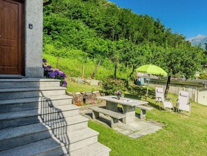 A stone staircase leading to a door, outdoor seating with a green umbrella, and a lush green hillside in the background. - Beautiful apartment for 6 people with WIFI, TV, patio and pets allowed (Era)