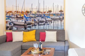 Ein Wohnzimmer mit einer Couch, einem Couchtisch und einem Gemälde eines Jachthafens.