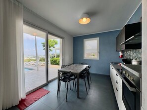 A modern kitchen with a dining area, large windows, and a view of the outdoors. - Stunning private villa for 7 people with WIFI, A/C, private pool, patio and panoramic view (Marina Di Ragusa)