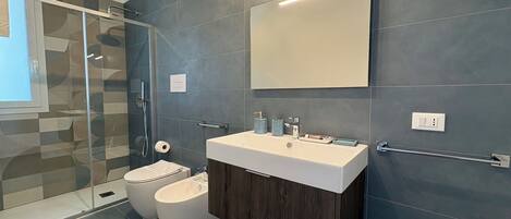 A modern bathroom with a glass shower enclosure, a white sink, and a dark wood vanity.