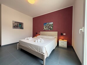 Ein Schlafzimmer mit einem Bett, zwei Nachttischen, einer Wandlampe und zwei gerahmten Bildern.