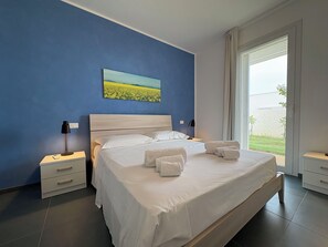 A bedroom with a large bed, two bedside tables, a nightstand, a window with blinds, and a painting on the wall. - Stunning private villa for 7 people with WIFI, A/C, private pool, patio and panoramic view (Marina Di Ragusa)