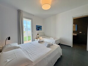 A hotel room with two beds, a window with curtains, a bedside lamp, a painting on the wall, and a bathroom visible through an open door. - Stunning private villa for 7 people with WIFI, A/C, private pool, patio and panoramic view (Marina Di Ragusa)