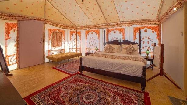 A room with a bed, a bench, and a patterned rug. - Heritage resort  (Jaisalmer)