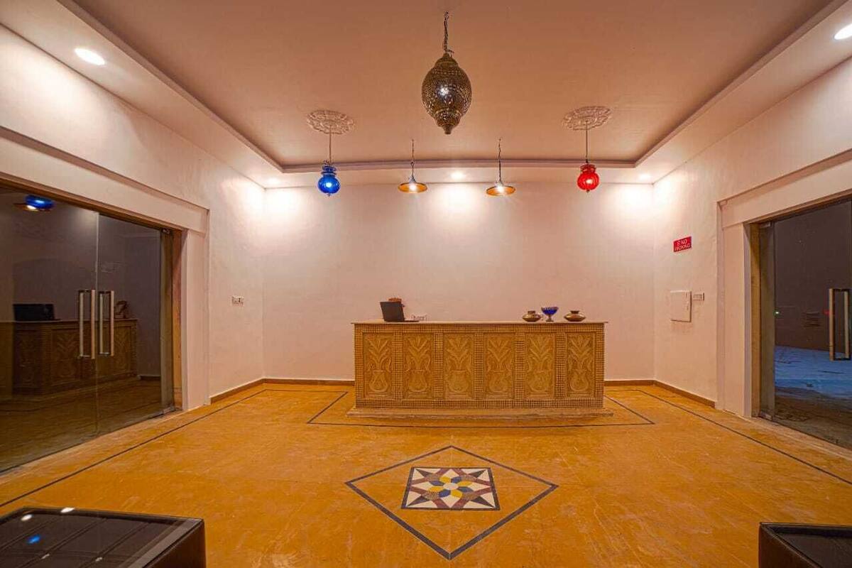Un área de recepción con un mostrador estampado, un diseño geométrico en el piso y luminarias colgantes.
